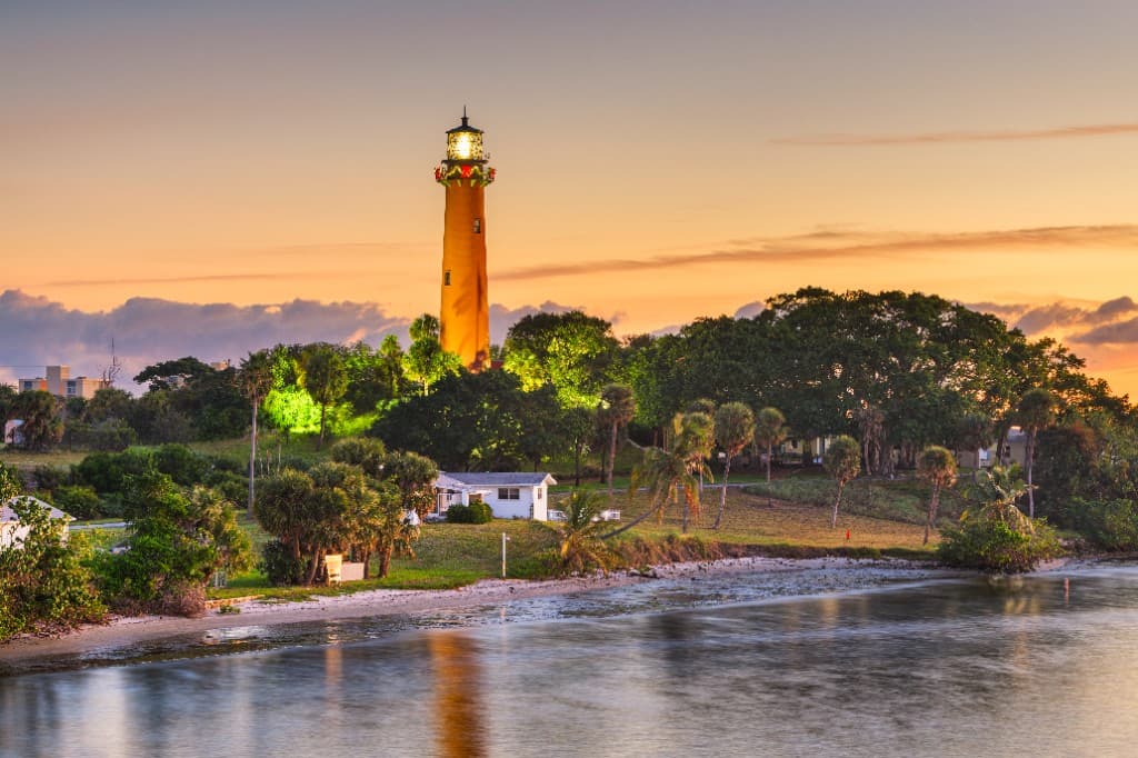 Jupiter Inlet at sunset with the lighthouse, calm water, and warm coastal light.