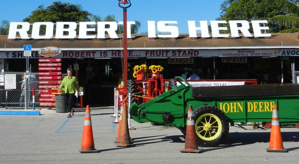 Robert Is Here fruit stand in Homestead with the large rooftop sign, farm wagon, and market entrance on a sunny Florida day.